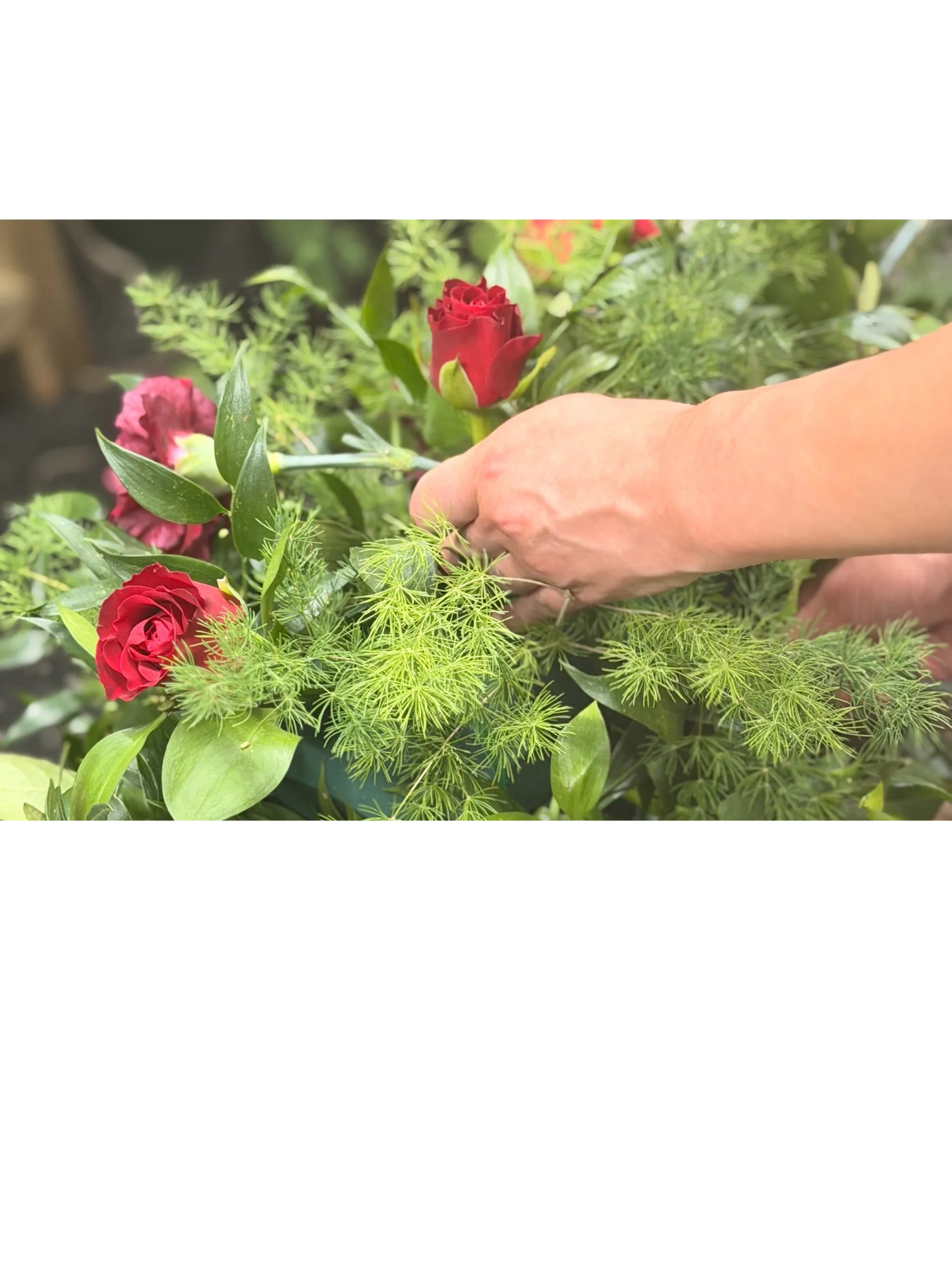 A florist carefully arranging red roses by hand